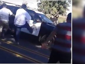 A police car, with the officer inside, was attacked by an angry mob in Fresno, Calif., Sunday. (YouTube screen grab)