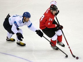 Team Finland's Juhamatti Aaltonen tries to check Team Canada's Corey Perry during their men's hockey game at the Bolshoy Ice Dome at the 2014 Winter Olympics in Sochi, Russia. (Al Charest/Postmedia Network/Files)