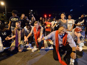 Clergy pray with protesters outside the Charlotte Police Dept. in Charlotte, N.C., after ignoring the curfew on Sunday, Sept. 25, 2016. A fifth day of protests against Keith Lamont Scott's fatal shooting remained largely peaceful after the release of the partial police vehicle dashcam and police body cam footage. (Jeff Siner/The Charlotte Observer via AP)