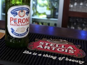 A bottle of Peroni beer sits on a Stella Artois beer mat in a pub in London, Tuesday, Oct. 13, 2015. The world's top two beer makers agreed Tuesday to join forces to create a company that would control nearly a third of the global market. AB InBev's brands include Budweiser, Stella Artois and Corona, while SABMiller produces Peroni and Grolsch. (AP Photo/Kirsty Wigglesworth)