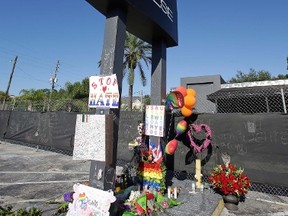 In this June 22, 2016 file photo, a makeshift memorial is seen at the base of the sign of the Pulse nightclub, scene of the recent mass shooting, in Orlando, Fla. Evolution and genetics seems to have baked a certain level of murder into humans as a species, but civilization has tamed some of that “inherited” savage beast in us, according to a new study.  (AP Photo/John Raoux, File)