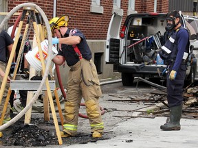 An unidentified Chatham-Kent firefighter pours a plastic pail full of charred debris into a hanging box sifter at the scene of Tuesday's fatal fire at 126 Nelson St. in Wallaceburg, as fire, police and members of the Ontario Fire Marshal continue their investigation on Wednesday September 28, 2016 in Wallaceburg, Ont. (Vicki Gough/Chatham Daily News)