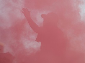 A Toronto FC fan celebrates while shrouded in smoke from a flare during a game earlier this season. (THE CANADIAN PRESS)