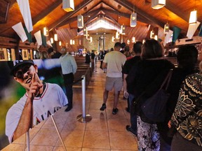 Mourners file past a photo of Miami Marlins pitcher Jose Fernandez during a memorial service at St. Brendan's Catholic Church, Wednesday, Sept. 28, 2016, in Miami. Fernandez was killed in a weekend boat crash along with two friends. (AP Photo/Wilfredo Lee)