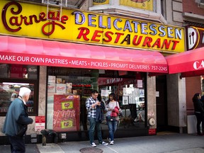 People pass the Carnegie Delicatessen in Manhattan. (Photo by Kevin Hagen/Getty Images)