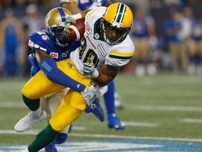 Edmonton Eskimos' John White (30) gets wrapped up by Winnipeg Blue Bombers' Bruce Johnson (25) during the first half of CFL action in Winnipeg Friday, September 30, 2016.