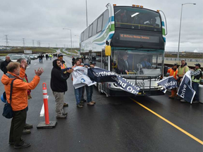 Workers hold a banner as a bus, carrying dignitaries, slices through during a celebration held on the Saskatchewan River Bridge to mark the grand opening of Northeast Anthony Henday Drive. (Ed Kaiser)