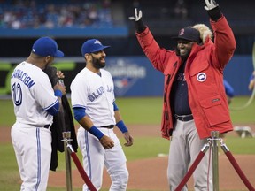Boston Red Sox designated hitter David Ortiz, right, tries on a Canada Goose winter jacket that was given to him as a gift by Toronto Blue Jays right fielder Jose Bautista, centre, and designated hitter Edwin Encarnacion before American League MLB baseball action in Toronto on Friday, September 9, 2016. (THE CANADIAN PRESS/Peter Power)