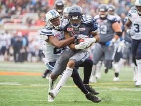 Alouettes' B.J. Cunningham (right) is tackled by Argonauts' Brandon Isaac (left) during first half CFL action in Montreal on Sunday, Oct. 2, 2016. (Graham Hughes/The Canadian Press)