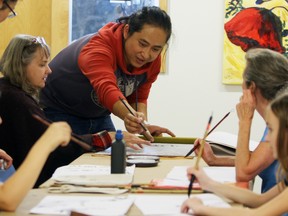 Pengyuan Wang teaches Chinese calligraphy to Patricia Vansperen, second from left, at Culture Days at the Tett Centre on Saturday. (Steph Crosier/The Whig-Standard)