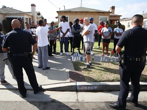 Los Angeles Police officers speak to neighbors and members of the community gathered around a makeshift memorial outside a residence on Sunday, Oct. 2, 2016. Officers shot and killed Carnell Snell Jr. in south Los Angeles on Saturday at the end of a car chase, sparking a protest by several dozen people angered by another fatal police shooting of a black man. (AP Photo/Damian Dovarganes)