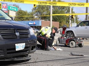 Constable Rick Carr, of the Greater Sudbury Police Service  traffic management unit places evidence markers at the scene where an elderly woman on a scooter was struck by a van at the corner of King street and Notre Dame Avenue,in Sudbury, Ont. on Monday October 3, 2016. The woman was sent to hospital with serious life threatening injuries.Gino Donato/Sudbury Star/Postmedia Network