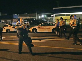 This photo taken Aug. 19, 2014, shows St. Ann Police Lt. Ray Albers raising his rifle at demonstrators on West Florissant Avenue in Ferguson, Mo. (Huy Mach/St. Louis Post-Dispatch via AP)