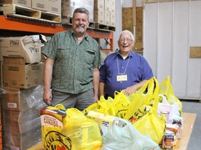 Claude Rocheleau and Bob LaBelle stand beside some of the donated items of food that was collected during the annual food drive.