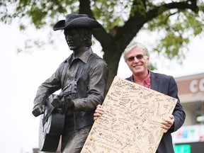 Colin Firth shows off a stomping board on Sunday that was signed the day a video was shot at the Stompin' Tom Connors statue in Sudbury. (Gino Donato/Sudbury Star)