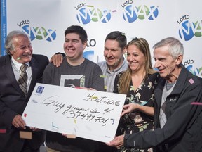 Patrick Lamothe and his wife Johanne Leblond, their son Yannick, centre, and Johanne's father Guy Leblond, right, all from Montreal, are presented with their cheque for the $37.5 million jackpot win in the September 30 Lotto Max draw by Guy Corbeil Tuesday, October 4, 2016 in Montreal. (THE CANADIAN PRESS/Paul Chiasson)