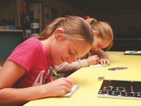 Avery Cummins, 11, and Meghan Pooley, 10, write stories Sept. 16 during the Fantastical Fiction writing workshop held at the Get-A-Way Youth Centre and led by award winning children’s author Susanne Heaton. Jasmine O’Halloran-Han Vulcan Advocate