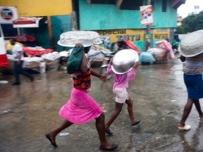 Women cover their heads with pans as they walk in a light rain brought by Hurricane Matthew in Port-au-Prince, Haiti, Tuesday, Oct. 4, 2016. Hurricane Matthew roared into the southwestern coast of Haiti on Tuesday, threatening a largely rural corner of the impoverished country with devastating storm conditions as it headed north toward Cuba and the eastern coast of Florida. AP Photo/Dieu Nalio Chery