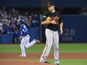 Baltimore Orioles starting pitcher Chris Tillman (front) looks on as Blue Jays slugger Jose Bautista rounds the bases after hitting a solo home run in the second inning on Tuesday night. (Frank Gunn/The Canadian Press)