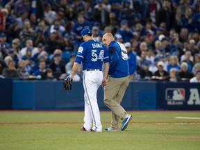 Blue Jays relief pitcher Roberto Osuna leaves the AL wild-card game with trainer George Poulis on Oct. 4, 2016. (MARK BLINCH/CP)
