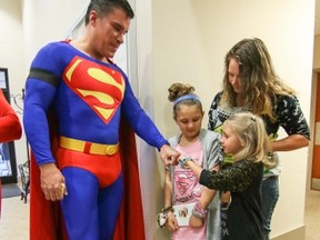 Zowie Sanders, gives a fist bump to John Suber, left, of Greenville, dressed as Superman, with her sister Lindsey Sanders, center, and their mother Brooke Starks, right, of Townville, during a wake service for Jacob Hall at Oakdale Baptist Church in Townville, S.C., Wednesday, Oct. 4, 2016. (Ken Ruinard/The Independent-Mail via AP, Pool)