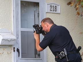 A Winnipeg police forensics officer takes pictures outside a house at 218 Newton Ave. on Wednesday morning. (Brian Donogh/Winnipeg Sun)