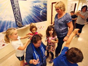 In the middle, letting the children cut her hair for cancer is Maureen Harburn, the educational assistant at St. James Catholic School.(Shaun Gregory/Huron Expositor)