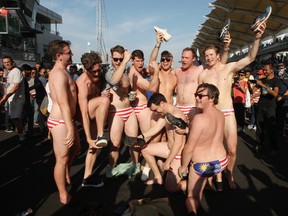 In this Sunday, Oct. 2, 2016 photo, Australian men celebrate in Budgy Smuggler-brand swimsuits decorated with the Malaysian flag at the conclusion of the Malaysian Formula One Grand Prix in Sepang, Malaysia. Malaysian authorities who have detained nine Australian men for three nights would regard their actions in stripping down to their briefs and drinking beer from shoes as premeditated, Australia's foreign minister said Wednesday, Oct. 5, 2016. (AP Photo)