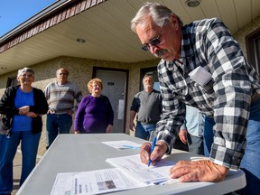 Andrew Bebris, a resident of Sandhills, signs a petition to stop the operation and further development of the Parkland Airport, at the Sandhills Community Hall, south of Spruce Grove on Monday, Oct. 3, 2016 - Photo by Yasmin Mayne.