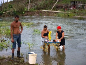 Residents wash their clothes in the Miel river after the passing of Hurricane Matthew, in Baracoa, Cuba, Thursday, Oct. 6, 2016. Leaving more than 100 dead in its wake across the Caribbean, Hurricane Matthew steamed toward heavily populated Florida with terrifying winds of 140 mph. (AP Photo/Ramon Espinosa)