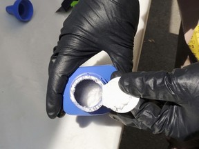 In this June 27, 2016 photo provided by the Royal Canadian Mounted Police, a member of the RCMP opens a printer ink bottle containing the opioid carfentanil imported from China, in Vancouver. Drug dealers have been cutting carfentanil and its weaker cousin, fentanyl, into heroin and other illicit drugs to boost profit margins. (Royal Canadian Mounted Police via AP)
