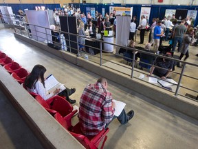 Job seekers fill out paperwork in the seats of the Agriplex as they join what is expected to be over 1,300 people at the London Economic Development Corp.'s London and Area Works Regional Job Fair at the Western Fair District in London. (CRAIG GLOVER, The London Free Press)