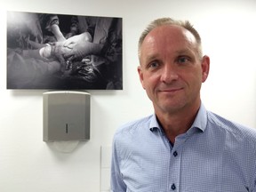 In this photo taken Monday, Sept. 19, 2016, professor Mats Brannstrom poses besides a photo showing the birth of a baby of a mother with a womb transplant at Stockholm IVF fertility clinic in Stockholm, Sweden. Brannstrom has made medical history by becoming the first doctor to deliver babies, five so far, from women with donated wombs, in a stunning advance that could lead to new insights into reproductive medicine and beyond. (AP Photo/ Dorothee Thiesing)
