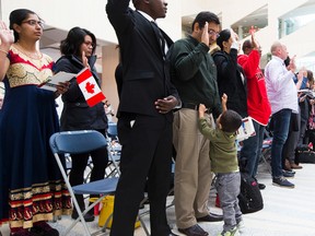 Satyam Patel takes the Oath of Citizenship as his son Krishiv,2, tries to get his attention during the Community Citizenship Ceremony at City Hall on Friday, October 7, 2016 in Edmonton. Greg Southam / Postmedia