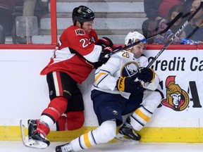 Buffalo Sabres' Zemgus Girgensons gets hit into the boards by Ottawa Senators' Chris Neil during pre-season NHL hockey action in Ottawa on  Oct. 7, 2016. (THE CANADIAN PRESS/Sean Kilpatrick)