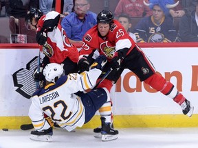Buffalo Sabres' John Larsson, middle, gets slammed to the ice by Ottawa Senators' Chris Neil as teammate Erik Karlsson stays on the puck on Oct. 7. (THE CANADIAN PRESS/Sean Kilpatrick)
