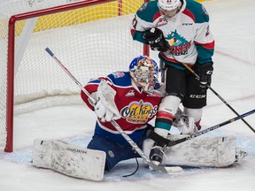 Liam Hughes of the Edmonton Oil Kings, makes a save despite the presence of Devante Stephens of the Kelowna Rockets at Rogers Place in Edmonton on October 7, 2016.