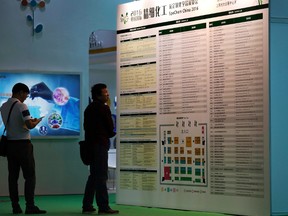 Visitors look at a directory of the vendors at the China International Chemical Industry Fair in Shanghai, China on Thursday, Sept. 22, 2016. Despite periodic crackdowns, people willing to skirt the law are easy to find in China’s vast, freewheeling chemicals industry, made up of an estimated 160,000 companies operating legally and illegally. Vendors said they lie on customs forms, guarantee delivery to countries where carfentanil is banned and volunteered strategic advice on sneaking packages past law enforcement. (AP Photo/Andy Wong)