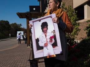 Phyllis Norden, from Red Wing, Minnesota, holds posters purchased during the grand opening of Paisley Park in Chanhassen, Minnesota on October 6, 2016. Paisley Park, the late pop star Prince's closely-guarded studio complex, opened to the public in Minnesota for a limited three-day peek inside. /(AFP PHOTO / STEPHEN MATURENSTEPHEN MATUREN/AFP/Getty Images)