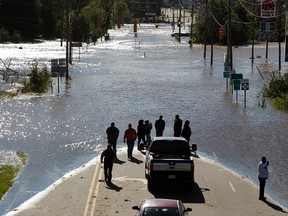 People stop to look and take photos of the floodwaters washing over highway 58 in Nashville N.C., seen from the highway 64 overpass, on Sunday, Oct. 9, 2016. Hurricane Matthew's torrential rains triggered severe flooding in North Carolina on Sunday as the deteriorating storm made its exit to the sea, and thousands of people had to be rescued from their homes and cars. (Chris Seward/The Charlotte Observer via AP)