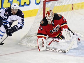 Winnipeg Jets winger Devin Setoguchi reaches for the puck during NHL action against the Calgary Flames at the Scotiabank Saddledome on January 16, 2014. (Colleen De Neve/Calgary Herald)