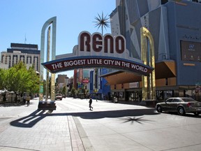 Pedestrians walk beneath the famous Reno arch as traffic passes on Virginia Street in downtown Reno, Nev. on Tuesday, Oct. 11, 2016. Detectives are reviewing witness accounts and some ``horrifying’’ cellphone video while they consider filing a criminal complaint after a pickup truck plowed into a crowd of people during a Native American rights demonstration in downtown Reno, the police chief said Tuesday. (AP Photo/Scott Sonner).