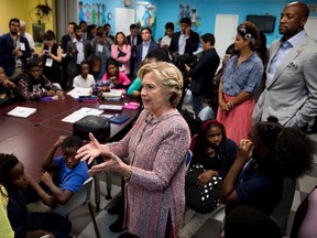 Democratic presidential candidate Hillary Clinton, accompanied by retired NBA basketball player Alonzo Mourning, right, and his wife Tracy, second from right, speaks with youth at the Overtown Youth Center in Miami, Tuesday, Oct. 11, 2016. (AP Photo/Andrew Harnik)