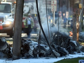 Smoke pours from the smoldering remains of a small plane that crashed on Main Street in East Hartford Conn., Tuesday, Oct. 11, 2016. Authorities said at least one person is dead and another is injured after a small airplane crashed near the Connecticut River. (Jim Michaud/Journal Inquirer via AP)