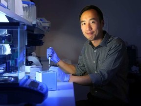 Paul Lem, CEO of Spartan Bioscience Inc. in Ottawa, sits beside the tiny square machine the local company has developed that analyzes DNA. JULIE OLIVER / POSTMEDIA