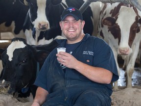 Dairy farmer Derek Van Dieten proudly wears his Toronto Blue Jays hat as sits among some of his 200 dairy cows at his farm in Seaforth, Ont. on Wednesday October 12, 2016. Van Dieten has pledged to donated 100 litres of milk to local food banks for every home run the Jays can hit during their post season playoff run. (CRAIG GLOVER, The London Free Press)