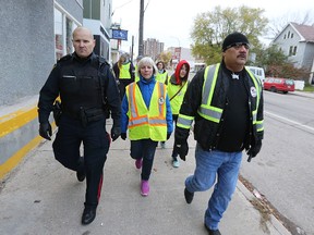 Winnipeg police Const. John Boehm (left) walks on Selkirk Avenue with a group led by Bear Clan Patrol organizer James Favel (right) on Wednesday night. Four general patrol officers walked the North End with members of the Bear Clan Patrol. (Kevin King/Winnipeg Sun)