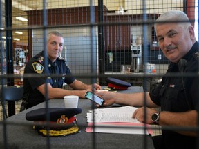 St. Thomas Police Chief Darryl Pinnell, left, and Aylmer Police Chief Andre Reymer try to scrape together enough bail money to escape their cell at Geerlinks Home Hardware Thursday morning. The chiefs-turned-cell mates raised money for St. Thomas Crime Stoppers at the non-profit's annual Bail or Jail fundraiser.