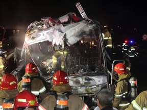 South Korean firefighters check a burned out bus on the Gyeongbu Expressway near the southeastern city of Ulsan, South Korea, Friday, Oct. 14, 2016. Twenty people, including the driver, were on the bus when it smashed into the guardrail and caught fire on the expressway, officials said. (Kim Yong-tae/Yonhap via AP)