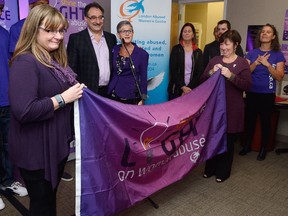Domestic abuse survivor Mary Meadows of St Thomas, left, and Lynn Gallant-Blackburn of Nova Scotia, whose sister was killed by her husband, hold a Shine the Light flag during a press conference at the London Abused Women's Centre on to Friday October 14, 2016. In behind are London developer Vito Frijia and LAWC executive director Megan Walker. The flag will fly over many London buildings during the month of November to raise awareness of the Shine the Light Campaign. (MORRIS LAMONT, The London Free Press)